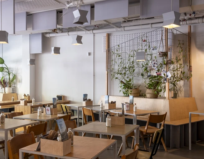 Kaffeesaurus Blick in das modern eingerichtete Café mit hellen Holzmöbeln und Pflanzen.View of the modern café with light wood furniture and plants.