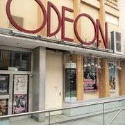 Odeon  Das Odeon Kino zeigt eine stilvolle Eingangsfassade mit großen Fenstern und einem markanten rotem Schriftzug.The Odeon cinema has a stylish entrance façade with large windows and striking red lettering.