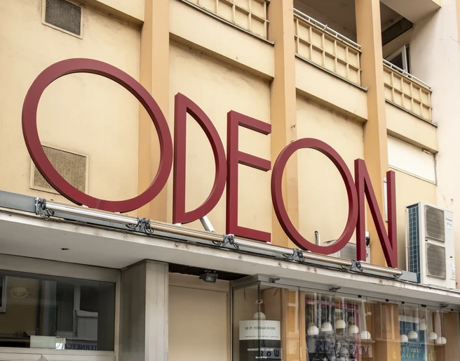 Odeon  Das Odeon Kino zeigt eine stilvolle Eingangsfassade mit großen Fenstern und einem markanten rotem Schriftzug.The Odeon cinema has a stylish entrance façade with large windows and striking red lettering.