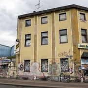 Sonic Ballroom Gelbes Haus mit grauen Dächern, urban und kreativ verziert, mit Sonic Ballroom Schriftzug.Yellow house with gray roofs, urban and creatively decorated, with Sonic Ballroom lettering.