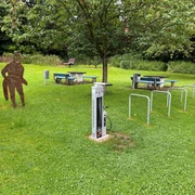 Rastplatz Petershagen  Rastplatz mit überdachten Picknicktischen, Spielskulptur, Fahrradständern und grüner Umgebung in Petershagen.