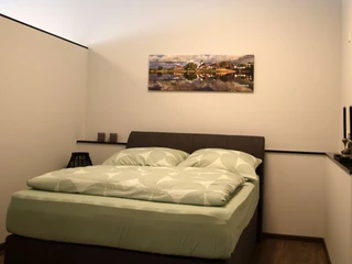 FeWo thelivingroom-schlafbereich.jpg Schlafbereich mit Doppelbett in moderner Ferienwohnung, helle Wände, ruhige Atmosphäre, Wandkunst.