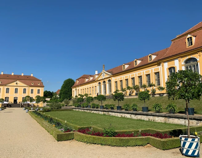 Barockgarten Großsedlitz Gebäude des Barockgarten Großsedlitz, im Vordergrund Rasen, Beete und Bäume, bei Sonnenschein.