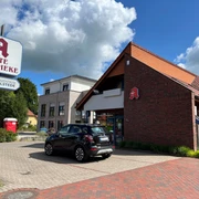 Alte Apotheke.jpg Das Bild zeigt eine rote Backsteingebäude, das die "Alte Apotheke" ist, mit einem markanten Eingang und einem daneben stehenden Auto.