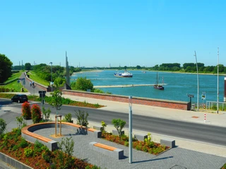 Ausblick auf den Rhein vom Hotel-Restaurant Zum Vater Rhein in Monheim am Rhein Blick auf den Rhein mit vorbeifahrendem Schiff, grüner Uferlandschaft und klar blauem Himmel in Monheim.