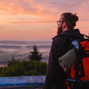 Ein Mann genießt den Sonnenaufgang auf dem Eisenberg bei Korbach