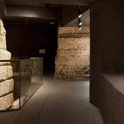Ubiermonument Im Bild sind historische Mauerwerke aus dem antiken Ubiermonument in Köln zu sehen. Im Vordergrund ein Zylinder, dahinter hell beleuchtete Steinwände, die die archäologische Atmosphäre unterstreichen.The picture shows historical masonry from the ancient Ubiermonument in Cologne. In the foreground is a cylinder, behind it brightly lit stone walls that emphasize the archaeological atmosphere.