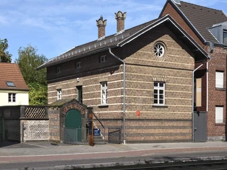 Roman grave Weiden Das Bild zeigt ein altes, gut erhaltenes Backsteinhaus mit schmalen Fenstern und gemauertem Schornstein. Der Eingangsbereich ist durch einen gewölbten Torbogen gekennzeichnet, der in einem ebenfalls aus Backstein gebauten Flügel mündet. The picture shows an old, well-preserved brick house with narrow windows and a brick chimney. The entrance area is characterized by a vaulted archway that leads into a wing also made of brick.