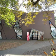 Museumsquartier Osnabrück Modernes Gebäude mit asymmetrischen Fenstern, umgeben von Herbstlaub in einer urbanen Umgebung.