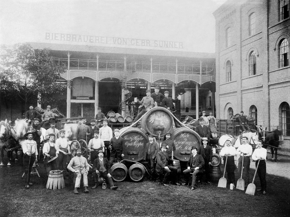 Historie09-Suenner_03b.jpg Historisches schwarz-weiß Bild von der Bierbrauerei Sünner mit Bierfässern und arbeitenden MännernHistorical black and white photograph of the Sünner brewery with beer barrels and working men