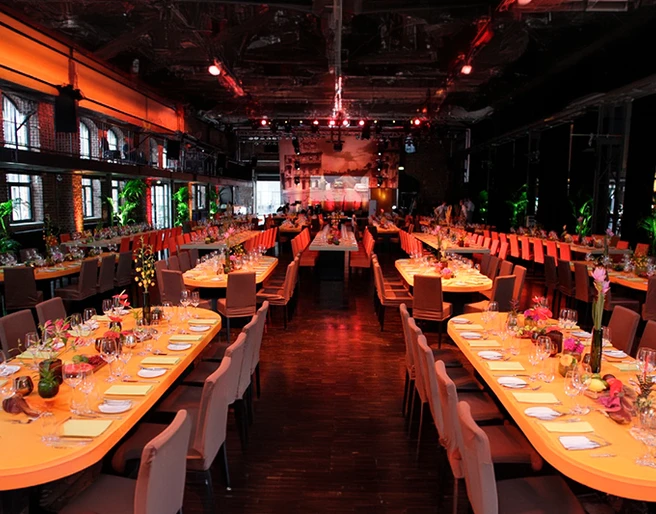 mSa Firmenevents Veranstaltungshalle im Industrielook mit gedeckten Banketttischen in atmosphärischer BeleuchtungEvent hall in an industrial style with covered banquet tables and atmospheric lighting