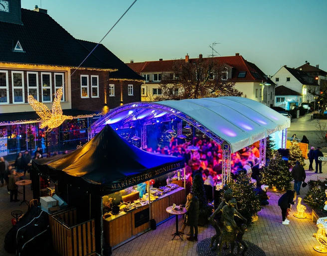 Gänseliesels Weihnachtslounge Weihnachtslounge mit glitzernden Lichtern, überdachten Marktständen und einem Weihnachtsengel in Monheim.