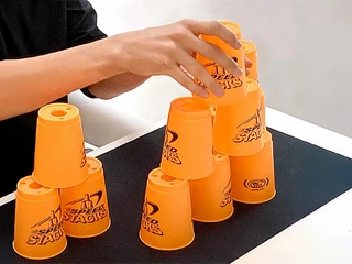 mSa Team-Bash Hände stapeln orangene Becher aufeinanderHands stacking orange cups on top of each other