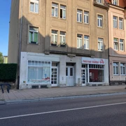 Fahrrad_Bäßler Fahrradladen in Pirna Mehrstöckiges Gebäude mit zwei Geschäften im Erdgeschoss, "Stromspar-Check" und "Fahrrad-Bäcker", bei sonnigem Wetter.