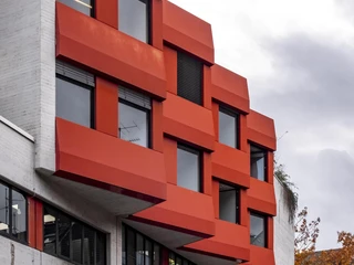 University of Music and Dance Die "Hochschule für Musik und Tanz" zeigt eine moderne Fassade mit markanten roten Fenstern und kantigem Design.The "Hochschule für Musik und Tanz" has a modern façade with striking red windows and an angular design.