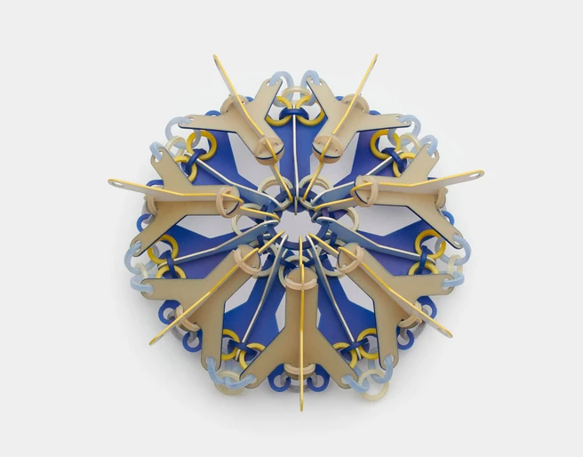 Svenja John, brooch "NOKOMIS" Bunte Brosche aus geometrischen Elementen, die sternförmig angeordnet sind auf grauem Hintergrund.Colorful brooch made of geometric elements arranged in a star shape on a grey background.