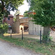 Spielplatz am Weserwall Spielplatz mit Holzklettergerüst und Rutschen, umgeben von Bäumen und Zäunen am Weserwall.