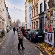 Körnerstraße  Körnerstraße in Köln-Ehrenfeld: Bunte Häuser, Kunstplakate an einem Baum, schlendernde Passant*innen.Körnerstraße in Cologne-Ehrenfeld: Colorful houses, art posters on a tree, strolling passers-by.