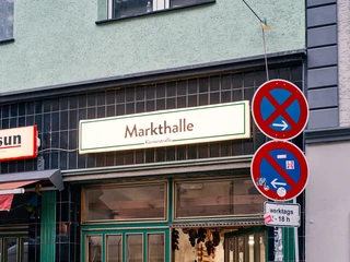 Körnerstraße  Eine geöffnete Tür zur "Markthalle" mit einladenden Schaufenstern, Fahrräder und Straßenschilder davor.An open door to the "market hall" with inviting shop windows, bicycles and street signs in front of it.