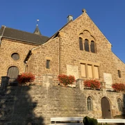 Ein steinernes Kirchengebäude mit Blumen geschmückt, im Sonnenlicht einer klaren, blauen Tageszeit.