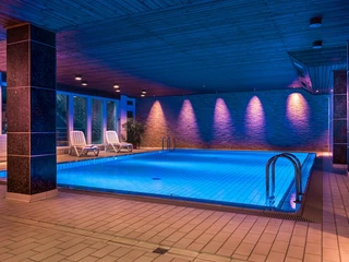 Schwimmbad im Hotel am Stadtpark, Hilden Hallenbad im Hotel am Stadtpark Hilden, stimmungsvoll beleuchtet mit blauen und violetten Lichtern.