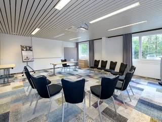 Tagungsraum  Tagungsraum mit Stuhlkreis, Leinwand und TageslichtMeeting room with a circle of chairs, a screen and daylight