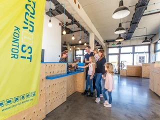 Innenraum des Tourist-Kontor Zwenkau  Das Bild zeigt den Innenraum des Tourist-Kontors Zwenkau, eine junge Familie lässt sich gerade am Tresen beraten.The picture shows the interior of the Tourist-Kontor Zwenkau, a young family is getting advice at the counter.