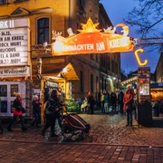 Weihnachtsmarkt am Connewitzer Kreuz - Weihnachten in Leipzig Blick auf den Eingang zum Weihnachten am Kreuz mit Leuchtreklame und Besuchern am Abend