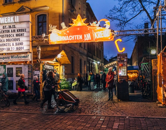 Weihnachtsmarkt am Connewitzer Kreuz - Weihnachten in Leipzig Blick auf den Eingang zum Weihnachten am Kreuz mit Leuchtreklame und Besuchern am Abend