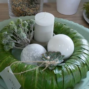 Adventsgesteck Ein dekorativer Adventskranz aus grünen Blättern mit Kerze, weißen Kugeln und einer Sukkulente.