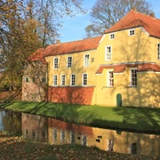 Manningaburg Pewsum Die gelbe Manningaburg von außen, Herbstlicht, davor der Wassergraben