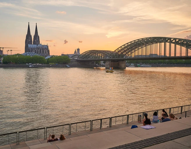 Rhine Boulevard Panoramablick auf den Rheinboulevard mit dem Kölner Dom und der eindrucksvollen Hohenzollernbrücke im Sonnenuntergang.Panoramic view of the Rhine boulevard with Cologne Cathedral and the impressive Hohenzollern Bridge at sunset.