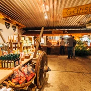 Gänsemarkt Eskildsen in Wermsdorf Eine alte Scheune in dem ein Wagen mit Produkten steht. Im Hintergrund ist eine Auschanlstation und ein Weihnachtsbaum.