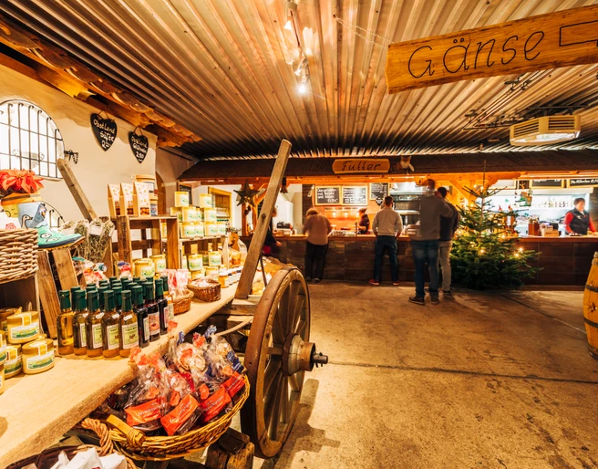 Gänsemarkt Eskildsen in Wermsdorf Eine alte Scheune in dem ein Wagen mit Produkten steht. Im Hintergrund ist eine Auschanlstation und ein Weihnachtsbaum.