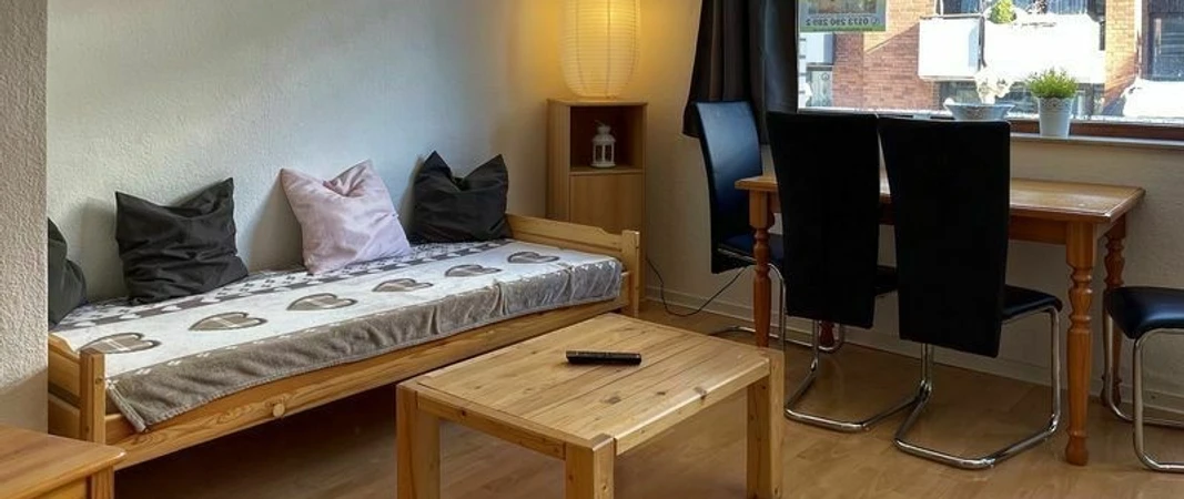 wohnzimmer_holighaus.jpg Wohnraum mit Holzmöbeln und zum Sofa umfunktionierten BettLiving room with wooden furniture and bed converted into a sofa