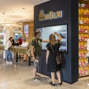 Tourist Information Köln Besucher nutzen interaktive Bildschirme in einer modernen Touristeninformation in Köln.Tourists interact at an info terminal inside a spacious, modern Cologne visitor centre.