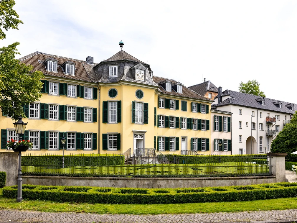 Herrenhaus Cromford Historisches Herrenhaus mit gelber Fassade, flankiert von grünen Fensterläden und gepflegter Gartenanlage.