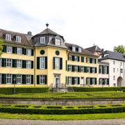 Herrenhaus Cromford Historisches Herrenhaus mit gelber Fassade, flankiert von grünen Fensterläden und gepflegter Gartenanlage.