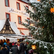 Schloss Trebsen Banner Advent im Schloss.png Man sieht ein Banner an der Hauswand vom Schloss Trebsen auf dem Advent im Schloss steht. im Vordergrund ist ein weihnachtlicher Stand und ein Weihnachtsbaum.