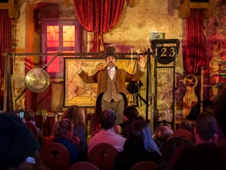 Schloss Trebsen weihnachtliche Theateraufführung Zusehen ist ein Schauspiler der als Entdecker verkleidet ist, vor einem Publikum. Auf der Bühe stehen Requisiten.