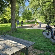 Bad Driburg_Wasser-Tretbecken Alhausen 4_Bad Driburger Touristik GmbH.jpg Ein Wasserkneippbecken in Alhausen umgeben von Bäumen und Spaziergängern, im Vordergrund ein Fahrrad.