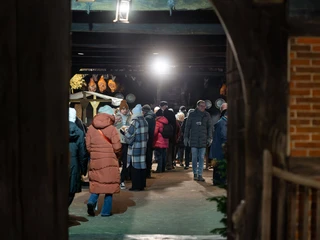 historischer-weihnachtsmarkt-bad-zwischenahn-bauernhaus-eingang.jpg Menschen in Winterkleidung besuchen abends den historischen Weihnachtsmarkt im Bauernhaus Bad Zwischenahn.