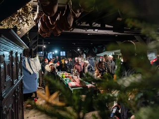 historischer-weihnachtsmarkt-bad-zwischenahn-bauernhaus-handwerkerkunst.jpg Menschen besuchen weihnachtlich geschmückten Markt in historischem Bauernhaus mit Handwerksständen.