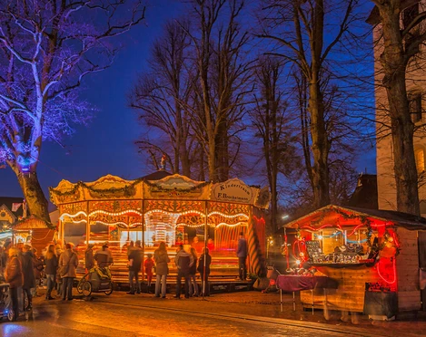 Hamberger Weihnachtsmarkt Beleuchtetes Karussell und Marktstände mit Besuchern auf dem Hamberger Weihnachtsmarkt bei Nacht.Illuminated carousel and market stalls with visitors at the Hamberg Christmas market at night.Oplyst karrusel og markedsboder med besøgende på Hambergs julemarked om aftenen.Verlichte draaimolen en marktkramen met bezoekers op de Hambergse kerstmarkt bij nacht.