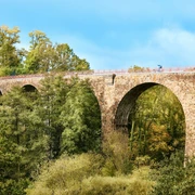 Viadukt Ruhrstraße Süd, Heiligenhaus Steinviadukt mit hohen Bögen überspannt eine bewaldete Schlucht, Radfahrer auf der Brücke.