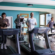 Fitnesstraining Menschen trainieren in einem modernen Fitnessstudio auf Laufbändern und einem Fahrradtrainer.