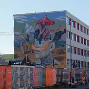 Mural Auf dem Bild ist eine farbenfrohe Wandmalerei zu sehen, die ein surrealistisches Motiv mit Figuren, Tieren und Landschaften darstellt.The picture shows a colorful mural depicting a surrealistic motif with figures, animals and landscapes.