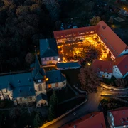 Weihnachtsmarkt Kohren-Sahlis Das Bild zeigt eine Luftaufnahme eines beleuchteten, historischen Gebäudekomplexes in herbstlicher Umgebung, in dem eine Veranstaltung mit zahlreichen Besuchern im Innenhof stattfindet.