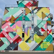 Mural Buntes geometrisches Wandbild an einem Hochhaus mit leuchtenden Farben und abstrakten Formen.Colorful geometric mural on a high-rise building with bright colors and abstract shapes.