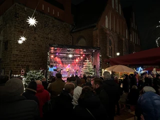 Adventszauber Nienburg (1).jpg Stimmungsvolle Adventsfeier in Nienburg mit beleuchteter Bühne, umgeben von Weihnachtsdekorationen.